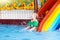 Child on swimming pool slide. Kids swim. Water fun