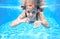 Child swims in pool underwater, happy active girl has fun