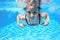 Child swims in pool underwater, happy active girl has fun under water, kid sport