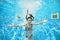 Child swims in swimming pool underwater, little active girl jumps, dives and has fun under water, kids fitness and sport