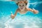 Child swims underwater in swimming pool, happy active boy dives and has fun under water, kids watersport. Children play