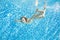 Child swims underwater in swimming pool, little active girl dives and has fun under water, kid fitness and sport