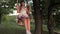 Child swinging on a swing in park in sun. young girl swinging on rope swing on an oak branch. teen girl enjoys flight on