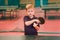 Child table tennis player holding a ball and a rocket in the gym