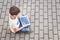 Child with tablet computer sitting outdoors. Education, learning, technology, friends, school concept. Top view.