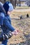 A child takes pumpkin seeds from her mother`s hand to feed the birds in the park in early spring