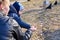 A child takes pumpkin seeds from her mother`s hand to feed the birds in the park in early spring