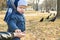 A child takes pumpkin seeds from her mother`s hand to feed the birds in the park in early spring