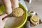 Child taking a healing warming foot bath with mustard powder, adding mustard powder to foot bath with wooden spoon.