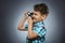 Child taking a picture using a retro rangefinder camera isolated grey background