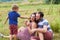 Child tickles his pregnant mother a blade of grass