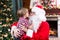 Child toddler boy kissing Santa Claus sitting near