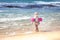 Child toddler girl in swimwear on beach standing in front of storming sea and ready to swim in during summer vacation concept fear