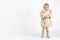 A child toddler in a light Soviet muton coat or sheepskin coat and gray felt boots is standing and looking at the camera on a