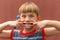 A child with a toothbrush in his hand shows a toothless mouth swelling his cheeks