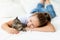 A child is torturing an animal, a little girl with a cat is lying on the bed, the concept of a child`s friendship with animals