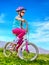 Child traveling bicycle in rainbow goggles and helmet in park.