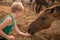 The child treats the horse with apples. A blonde girl feeds a brown horse from her palms. The boy holds out a treat to