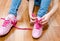 Child tying her shoes sitting on the floor at home