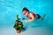 Child underwater in the pool decorates the Christmas tree with Christmas toys. Portrait. Shooting under water. Horizontal orientat