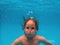 A child underwater swims in a pool with clear blue water