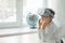 A child with a virtual reality headset is sitting at the table indoors at home. A girl exploring the world of virtual reality