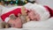Child wakes up before Christmas. Little boy in Santa hat and Christmas pajamas lying in white bed hugging plush toy