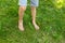 The child walks barefoot on the green grass. The concept of hardening, prevention of flat feet, meditation.