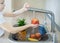 Child washing fresh apple in running water in kitchen sink. Sanitizing fruits and vegetables before eating. Hygiene concept.