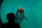 A child is watching a dolphin that is behind the glass of the aquarium