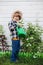 Child watering  summer garden from a watering can. Kid works in the garden in summertime. Baby boy is playing with water. Work for