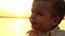 Child waving his head in the camera against the backdrop of the setting sun