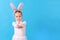 A child wearing a white rabbit. A little girl stretches an Easter egg in her hands. Cute bunny, holiday symbol. Bright