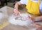 Child wearing yellow apron, playing with flour on table. Close-up picture of hands, drawing shapes on flour. Bakery master class
