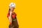 Child wears helmet and working overalls holds drill in his hands. Boy 9-10 years old imitates builder, yellow background. Copy