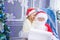 A child whispers a wish in Santa`s ear, Santa reads a letter at the Christmas tree, the concept of new year and Christmas