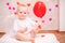 Child with white feather wings holds  red balloon in the shape of a heart, the symbols of Valentine`s Day