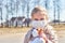 A child with white hair in a jacket and medical mask. Prohibition of school attendance. insulation