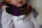 Child white jacket with scarf around his neck measures his body temperature using electronic thermometer