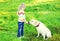 Child and white labrador retriever dog on grass in summer