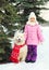 Child with white Samoyed dog in red scarf near christmas tree in winter