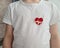 Child in white shirt with heart emblem on chest