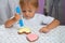 The child in a white t-shirt sits at a table and draws cream on cookies. Preparation and decoration of food