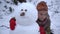 A child in the winter in the park sculpts a snowman.