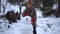 A child in the winter in the park sculpts a snowman.