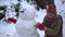 A child in the winter in the park sculpts a snowman.