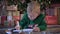 Child writes letter with wishes for gift for Santa Claus. Small blond boy in green sweater lies on floor near Christmas