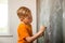 Child writing on chalkboard. Back to school. Kid with chalk in hand in class. Thinking pupil
