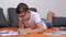 Child Writing with a Pen in a Notebook, Lying on an Orange Bedspread in Room