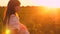 Child yawns in arms of the mother, baby wants to sleep, walk of mom and daughters at sunset in the park in summer